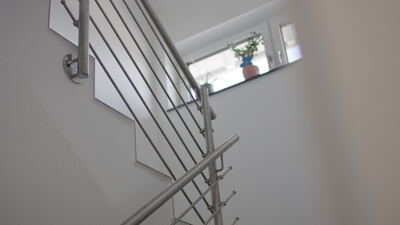 Moderne Innentreppe mit Edelstahlgeländer und Fenster