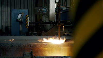 Flamme und Funken bei der Metallbearbeitung in einer dunklen Industriehalle