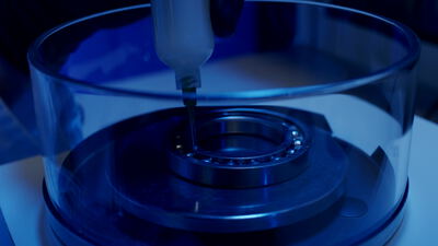 Schmierung eines Kugellagers mit feiner Dosiernadel bei blauem Licht