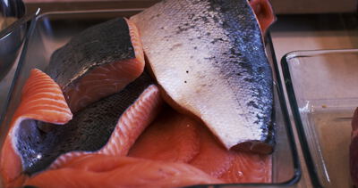 Frische Lachsfilets mit Haut liegen in einer gläsernen Auflaufform