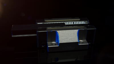 Blaue Linearführung mit Führungswagen auf dunklem Hintergrund