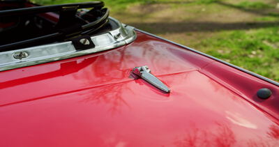 Motorhaube eines roten Oldtimer Sportwagens mit Chromverschluss