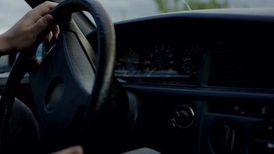 Hand am Lenkrad beim Autofahren im Fahrzeuginnenraum