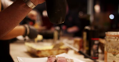 Hand würzt ein saftiges Steak mit Gewürzen bei einer Kochshow