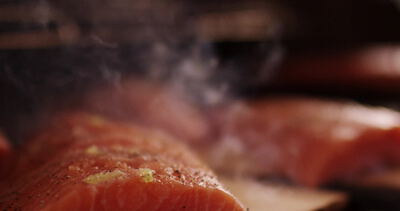 Frische Lachsfilets räuchern auf Zedernholzbrett über dem Grill