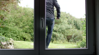 Maskierter Einbrecher geht mit Werkzeug durch den Garten am Hausfenster Maskierter Einbrecher geht mit Werkzeug durch den Garten am Hausfenster, Einbruch, Einbruchschutz und Eindringling als 4K