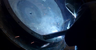Schweißer verschweißt ein großes Metallbauteil mit hellem Lichtbogen