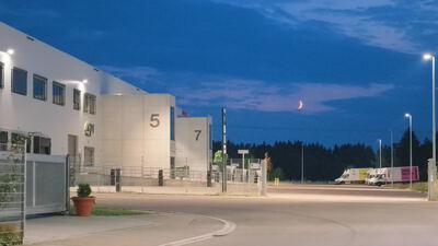 Gewerbehalle liegt in der Abenddämmerung mit parkenden Lieferwagen