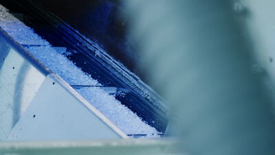 Kunststoffflocken rutschen über eine Metallrutsche in die Maschine Kunststoffflocken rutschen über eine Metallrutsche in die Maschine, Recyclingmaschine, Kunststoffrecycling und