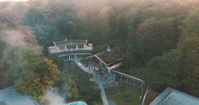 Drohne fliegt über moderne Villa im herbstlichen Morgennebel