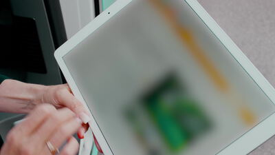 Hände einer älteren Frau bedienen einen weißen Tablet Computer