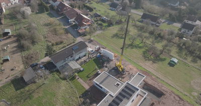 Luftaufnahme fliegt über Wohngebiet mit Baustelle und Kran