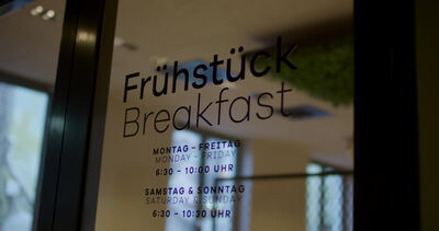 Frühstücksschild an Glastür informiert über Öffnungszeiten im Hotel