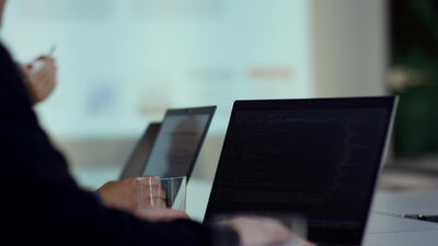 Person tippt Programmiercode am Laptop im hellen Büro