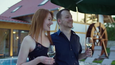 Paar stößt mit Weißwein im Garten eines Wellnesshotels an