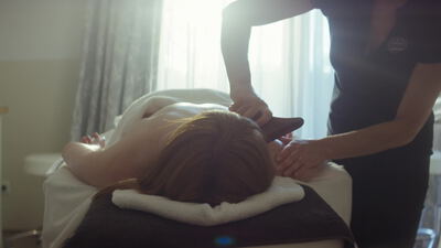 Frau entspannt bei einer Rückenmassage im Wellnessbereich
