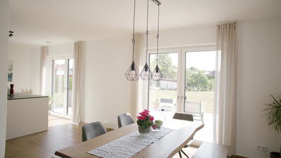 Moderner heller Essbereich mit Pendelleuchten und Blick in den Garten