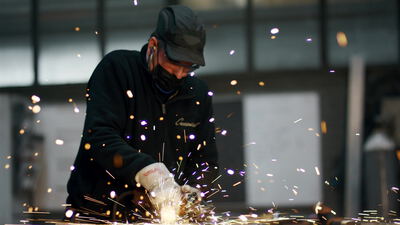 Handwerker schleift Metall mit einem Winkelschleifer und Funkenflug