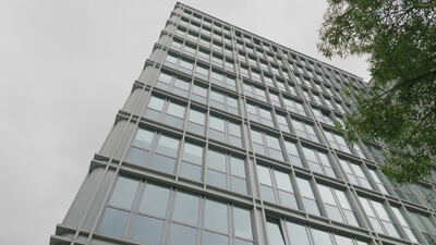 Glasfassade eines Wolkenkratzers ragt steil in den bewölkten Himmel: Wolkenkratzer Glasfassade, Glasfassade Hochhaus