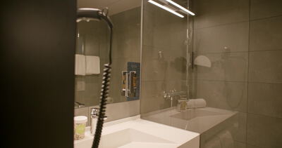 Beleuchteter Spiegel hängt über Waschbecken im modernen Hotelbadezimmer