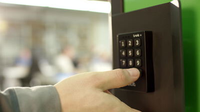 Finger drückt eine Zahlentaste am elektronischen Türschloss