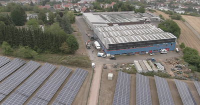 Luftaufnahme einer Industriehalle mit großer Photovoltaikanlage