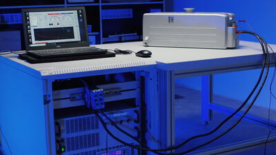 Technischer Versuchsaufbau mit Laptop und Messgeräten auf einem Labortisch bei blauem Licht, Computer, Bildschirm und