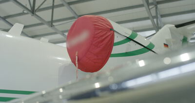 Triebwerk eines Privatjets mit roter Schutzabdeckung und „Remove Before Flight“-Anhänger im Hangar