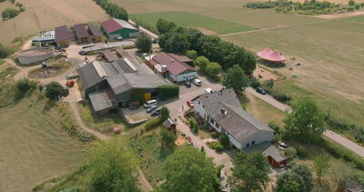 Vogelperspektive auf eine weitläufige landwirtschaftliche Hofanlage mit Wohnhaus