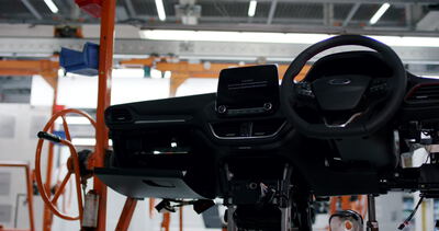 Vormontiertes Auto-Armaturenbrett mit Lenkrad und Infotainment-Bildschirm auf einer Produktionslinie