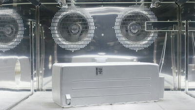 Weißer Behälter im Inneren einer technischen Prüfkammer aus Edelstahl mit Ventilatoren