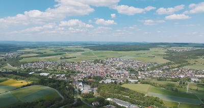 Weite Luftaufnahme einer deutschen Kleinstadt eingebettet in grüne Hügellandschaft und Felder